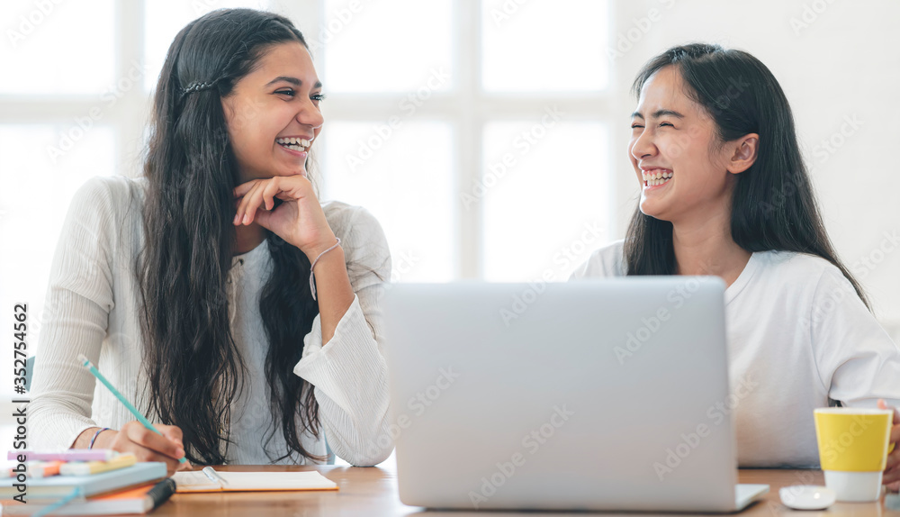Two young women talking and working together with happiness in contemporary room. Two young women talking and working together with happiness in contemporary room.