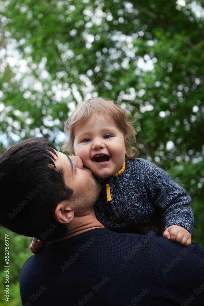 A cute little blonde haired, blue eyed boy plays with his Dad in an outdoor field, fathers day A cute little blonde haired, blue eyed boy plays with his Dad in an outdoor field, fathers day