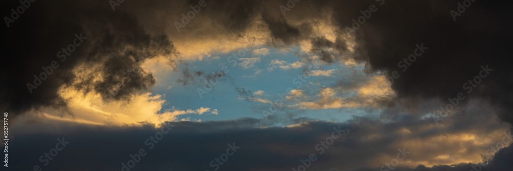 Panorama dramatic clouds illuminated rising of sun floating in sky. Natural weather, meteorology background. Soft focus, motion blur sky natural meteorology cloudscape. Panorama dramatic clouds illuminated rising of sun floating in sky. Natural weather, meteorology background. Soft focus, motion blur sky natural meteorology cloudscape.