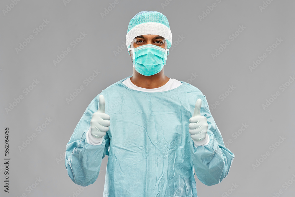 medicine, surgery and people concept - indian male doctor or surgeon in mask and protective wear over grey background