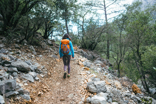 A girl with a backpack goes along a mountain trail.