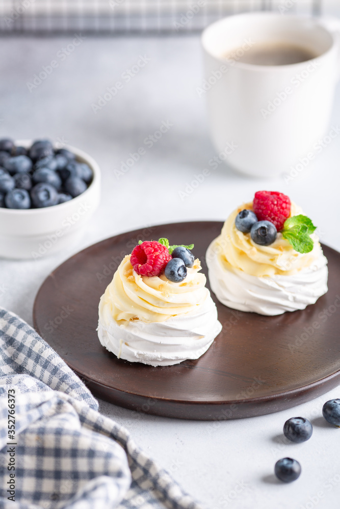 Coffee mug and Pavlova cake with whipped cream and fresh berries on wooden plate. Romantic breakfast Coffee mug and Pavlova cake with whipped cream and fresh berries on wooden plate. Romantic breakfast