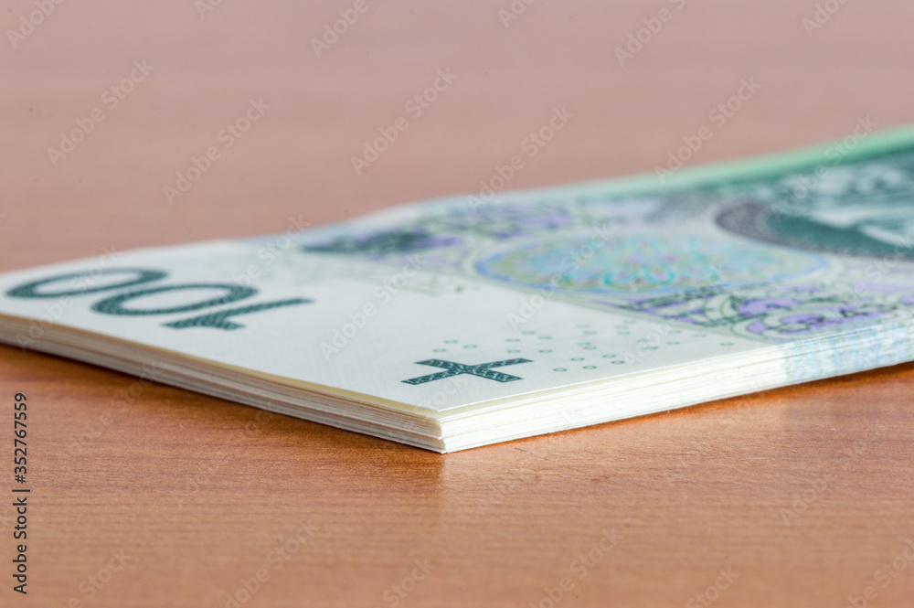 Stack of 100 PLN banknotes on wooden table. Stack of 100 PLN banknotes on wooden table.