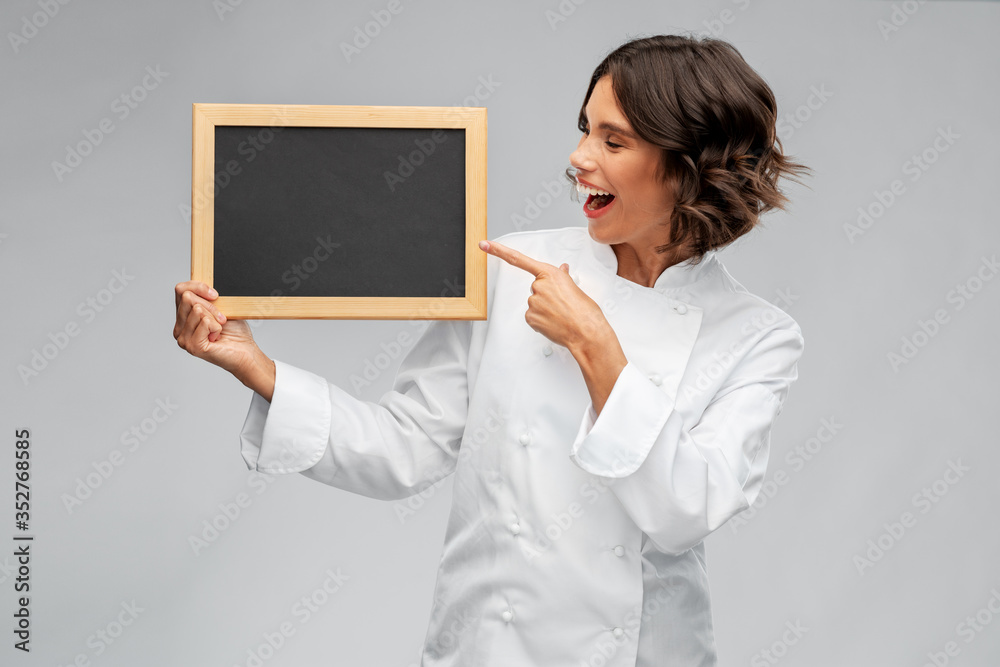 cooking, advertisement and people concept - happy smiling female chef holding black chalkboard over grey background cooking, advertisement and people concept - happy smiling female chef holding black chalkboard over grey background
