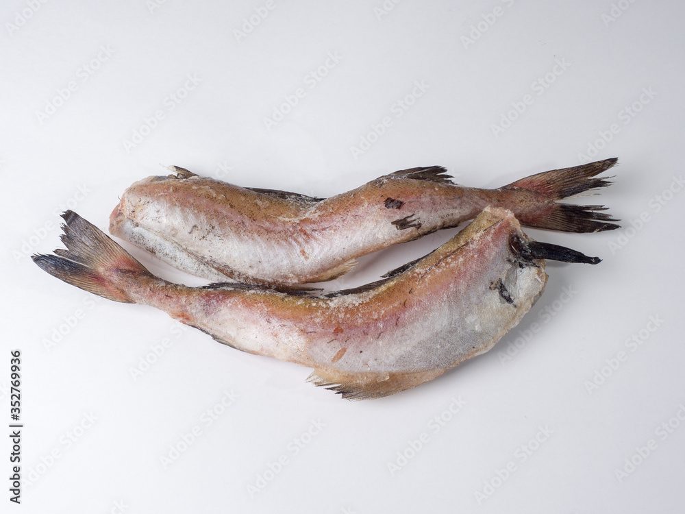Frozen carcasses of pollock fish on a white background. Top view