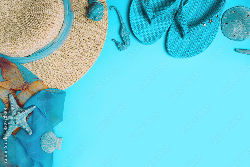 Summer fashion on blue background. Flip flops, seashells, and straw hat with scarf. Flat lay, top view with copy space. - obrazy, fototapety, plakaty 