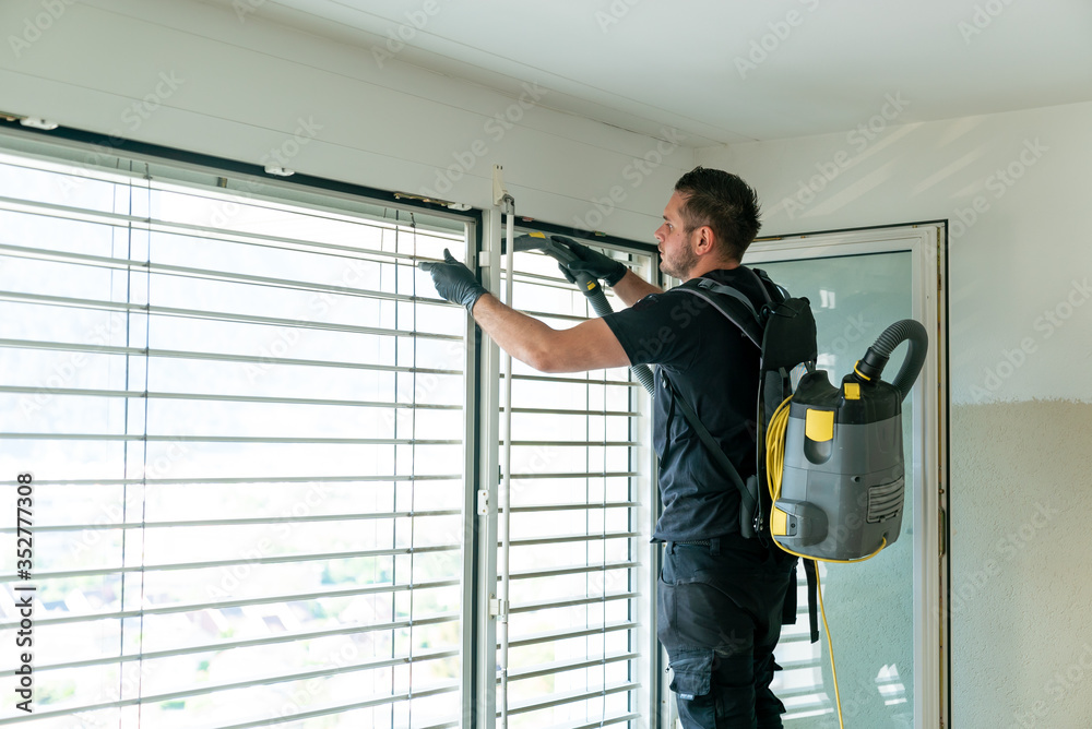 professional cleaner vacuum cleaning window blinds in an apartment in a high-rise building professional cleaner vacuum cleaning window blinds in an apartment in a high-rise building