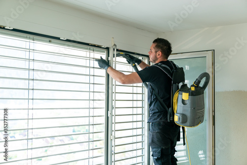 professional cleaner vacuum cleaning window blinds in an apartment in a high-rise building