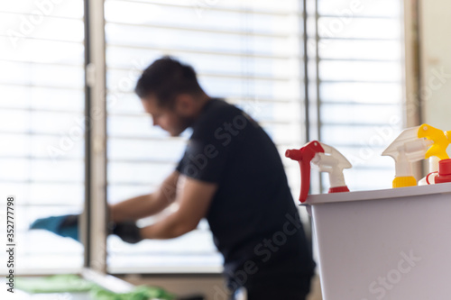 selective focus of cleaning supplies and a window cleaner in the background