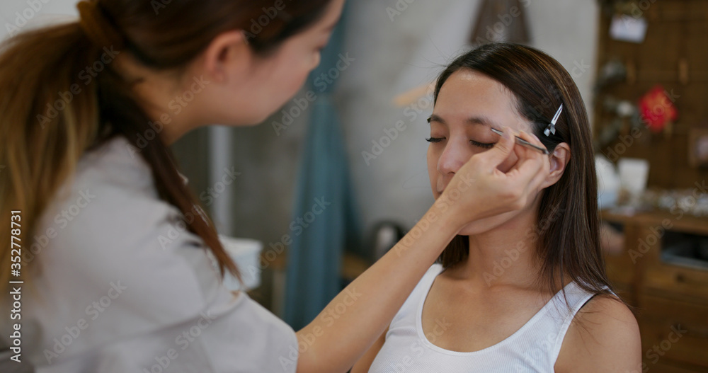 Make up artist shaping eyebrow on female model at studio Make up artist shaping eyebrow on female model at studio