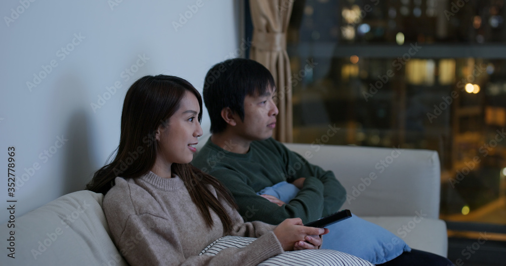 Couple watch tv together at home in the evening Couple watch tv together at home in the evening