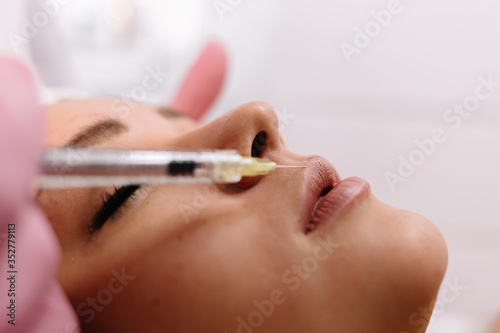 Woman receiving injections in lips zone. Close up of hands of cosmetologist making injection in female lip. Plastic surgery concept.Cosmetological clinic.Beauty Treatment.Cosmetology skincare concept.