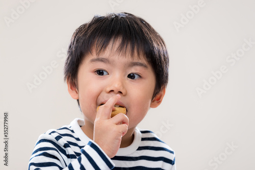 Asian kid boy eat cookie on white background