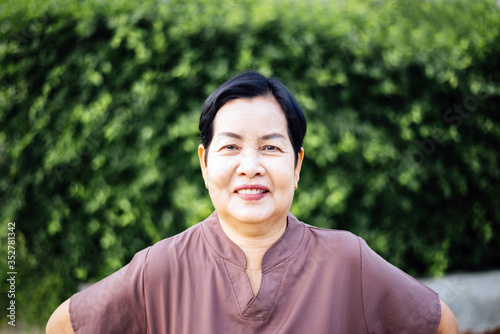 Mature asian woman standing at public park,Happy and smiling,Senior care insurance concept