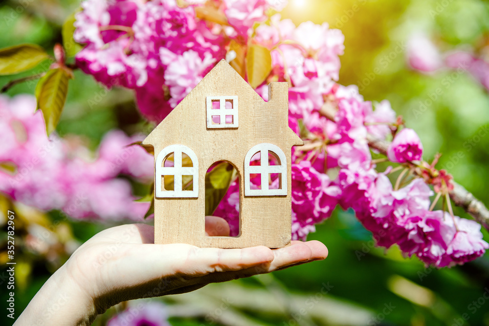 The girl holds the house symbol against the background of blossoming Sakura
The girl holds the house symbol against the background of blossoming Sakura