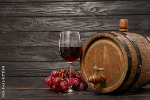 Wooden barrel and glass of wine on dark background