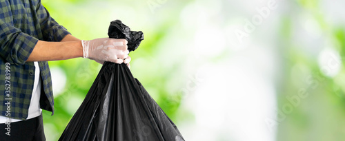 Fotografie close up man hand hold black trash bag to go to throw in the bin isolated (clipp