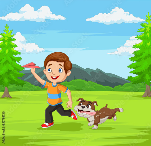 Happy boy playing paper airplane with his pet in the park