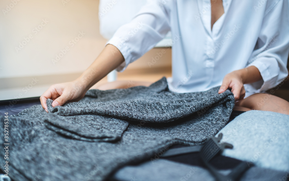 Fototapeta premium Closeup image of a woman folding clothes and packing luggage for a trip