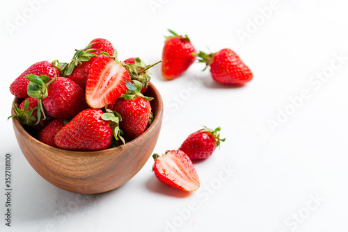 Wooden bowl with fresh natural ripe juicy red strawberry fruits on a white background.