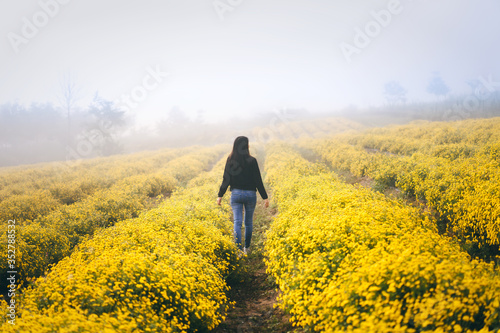 Adult asia traveller woman walking relax in yellowe park field on morning.