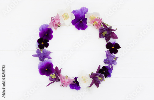 Flowers flat design. Floral round  frame, flowers wreath with   violet , purple, pink white  flowers. Template with copy space on white wooden board. Viola , Aquilegia,  Anemone flowers.