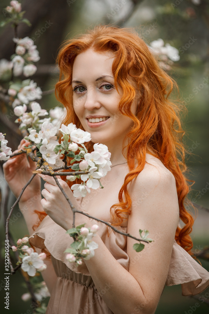 Fototapeta premium red-haired girl in a blooming garden