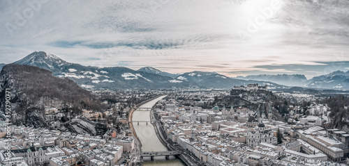 Aerial drone shot view of snowy Salzburg city old town by river in the morning with Salzburg Cathedral Hohensalzburg