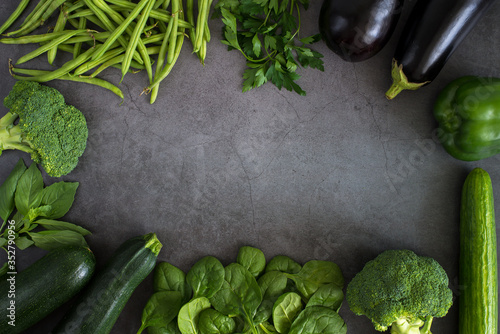 Green vegetables, healthy, vegetarian food parsley, basil, cucumber, broccoli, green bell pepper, zucchini, bean sprouts, spinach. Top view heathy raw food frame, leaf vegetables on dark background