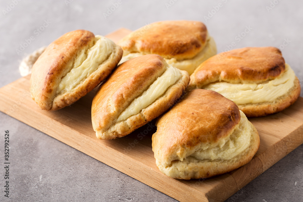 Wood board with hot homemade buns stuffed with cottage cheese. Selective focus.