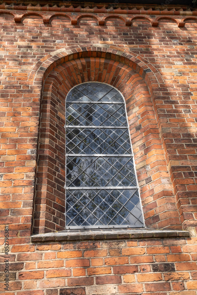 old church window with shadows around and colored bricks