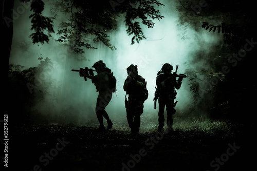 The action soldiers walking hold weapons with smoke light at night time background.