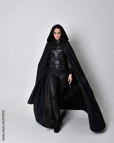 Foto fantasy portrait of a woman with red hair wearing dark leather assassin costume with long black cloak