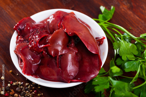 Image of raw rabbit liver with garlic and greens