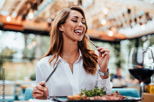 Photo Young beautiful and happy woman enjoying in delicious meal in luxurious restaurant