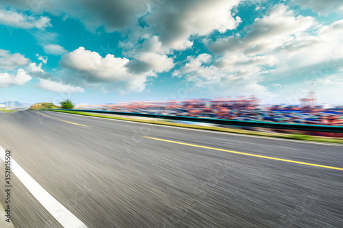 Motion blurred asphalt road and container port terminal landscape under blue sky. © ABCDstock