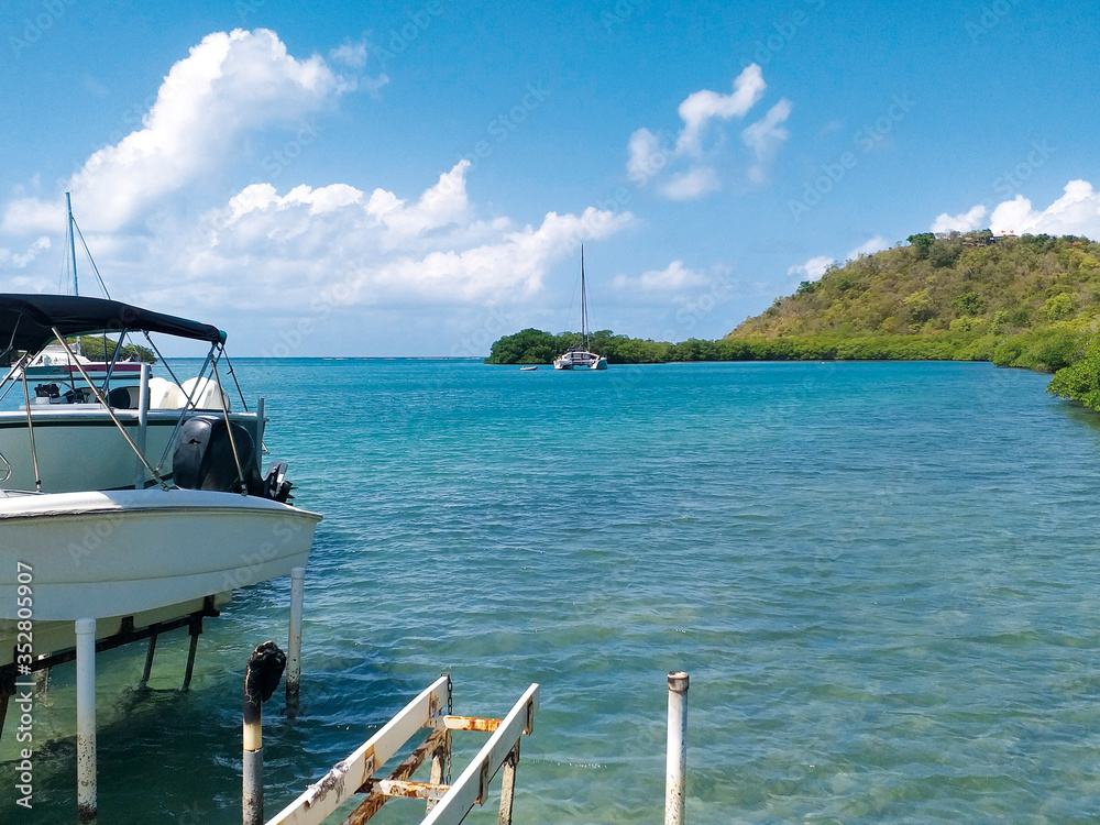 Turquoise waters of the Caribbean Sea with pleasure boats and lush vegetation. Idyllic tropical landscape.