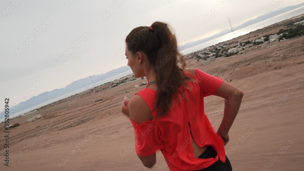 Brunette girl jogging along the road at seashore Brunette girl jogging along the road at seashore