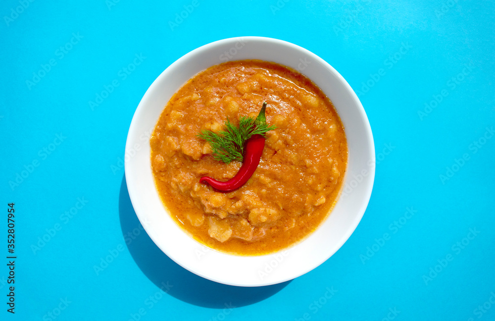 Famous traditional Arabic cuisine - peeled fava beans with chili in white bowl on blue background. Top view. Foul Mudammas, egyptian beans. Famous traditional Arabic cuisine - peeled fava beans with chili in white bowl on blue background. Top view. Foul Mudammas, egyptian beans.
