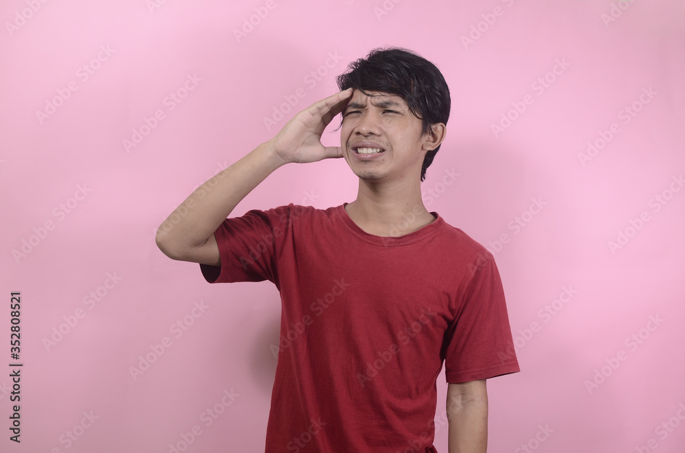 Men with tired and sick expressions. Asian men wearing red t shirts isolated on a pink background