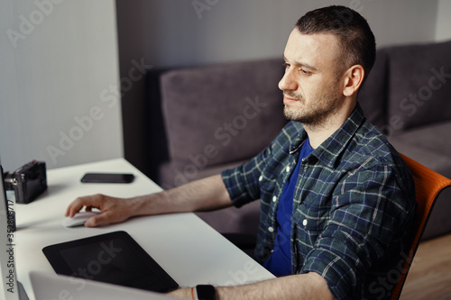 Handsome freelancer man working remotely from home. Young male working on his computer