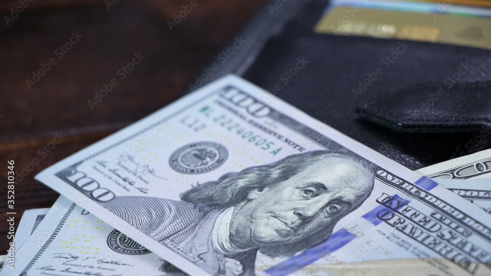 The hundred-dollar bills are on the wallet with the credit cards. Getting a loan or credit in US dollars. The calculation of the payment at the cashier.USA Dollar economy for business and finance The hundred-dollar bills are on the wallet with the credit cards. Getting a loan or credit in US dollars. The calculation of the payment at the cashier.USA Dollar economy for business and finance