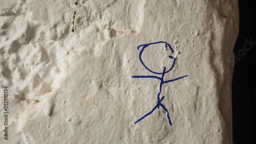Blue stick figure drawn on bumpy wall