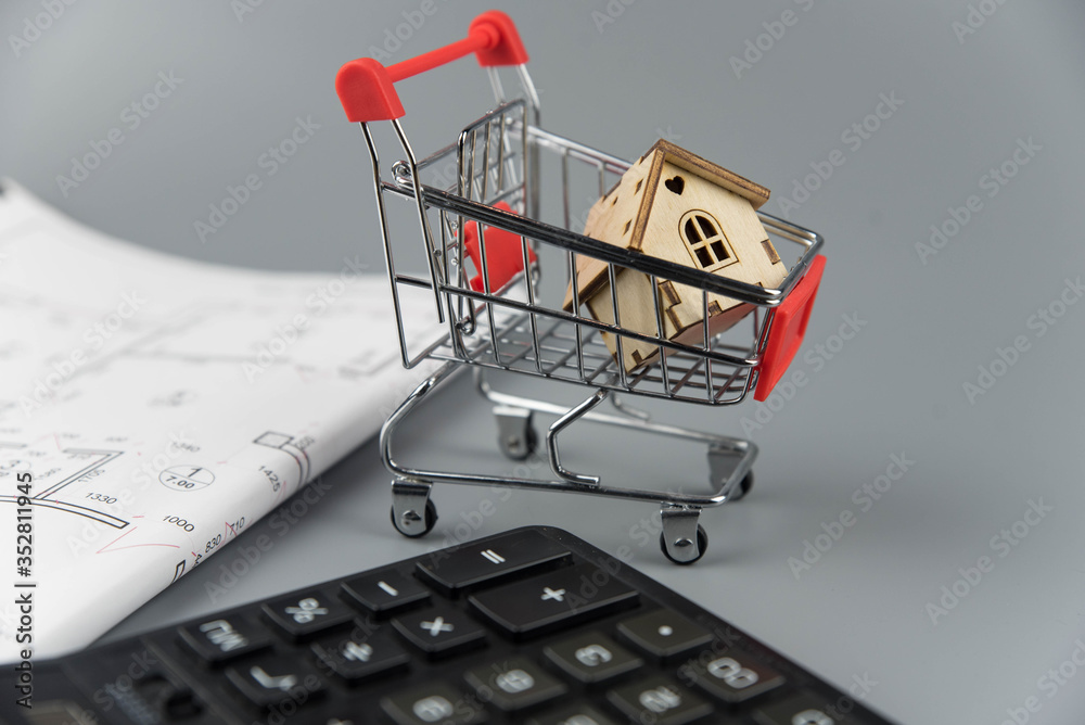 Buying a house, building repair and mortgage concept. Estimation real estate property with loan money and banking. House in shopping cart on grey background.