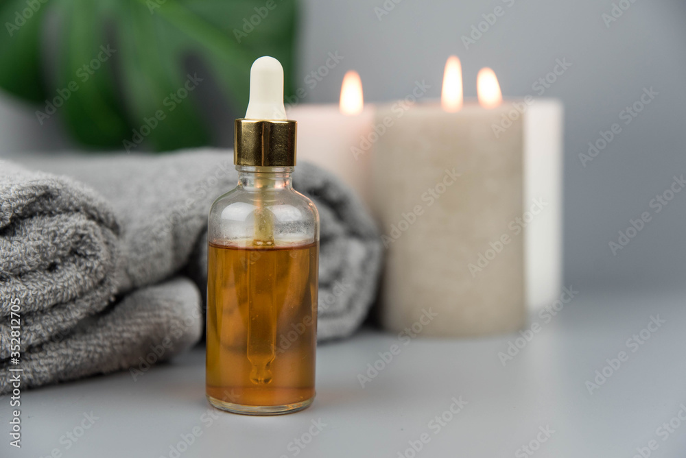 Towel with aromatic candles and bottle with natural organic oil essence serum. Aromatherapy and beauty. Concept set of harmony, balance and meditation, spa, massage, relax, beauty spa treatment.