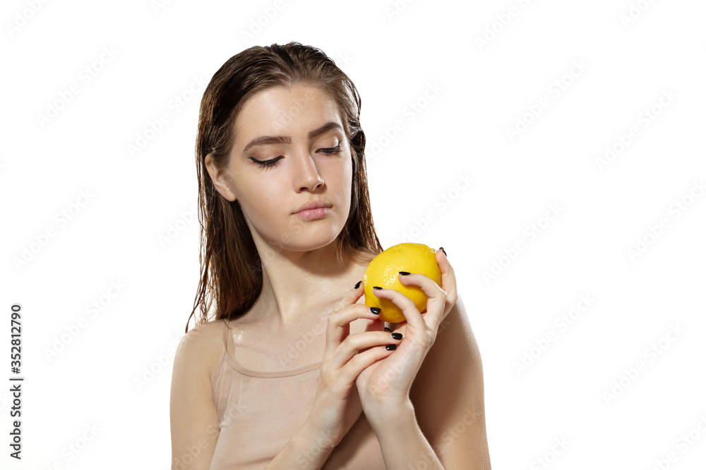 Portrait of beautiful young woman with fresh lemon near face over white background. Concept of cosmetics, makeup, natural and eco treatment, skin care. Shiny and healthy skin, fashion, healthcare. Portrait of beautiful young woman with fresh lemon near face over white background. Concept of cosmetics, makeup, natural and eco treatment, skin care. Shiny and healthy skin, fashion, healthcare.