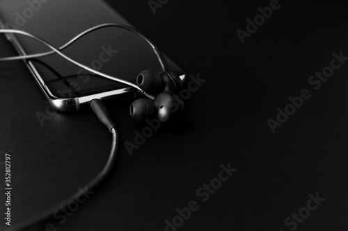 Black Headphones and Mobile phone on a black background