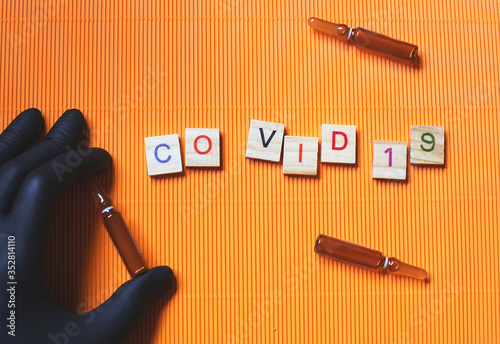 Header/banner COVID-19 concept orange background with ampuls where possible vaccine is ready. Pandemic deseas. World Health Organization officially named Coronavirus disease as COVID-19. photo