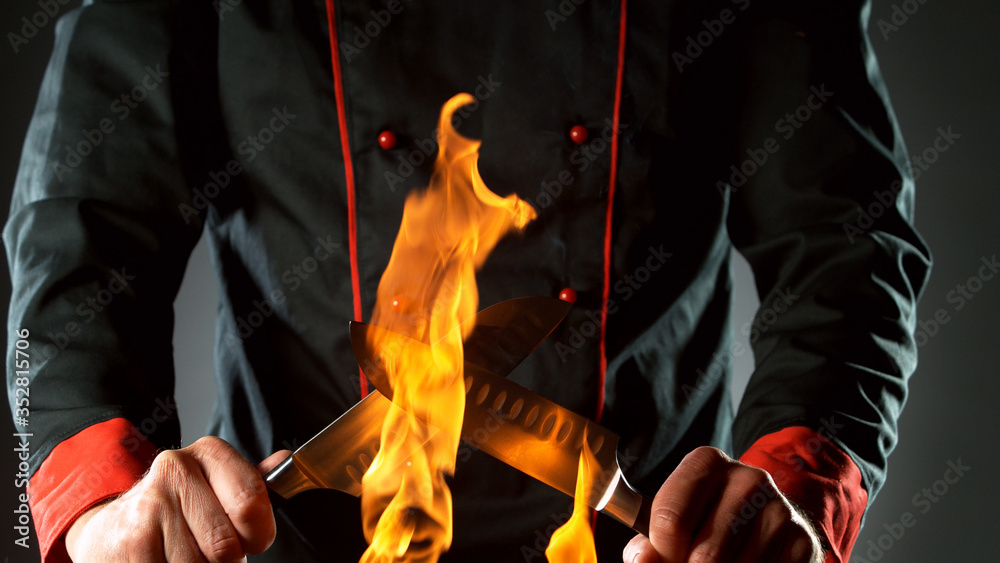 Closeup of chef holding knives in fire
