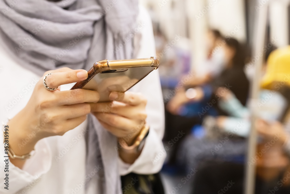 close up hand woman holding mobile phone or smartphone in subway train transit system public.